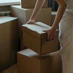 A woman packing cardboard boxes in her new apartment, symbolizing moving and relocation.